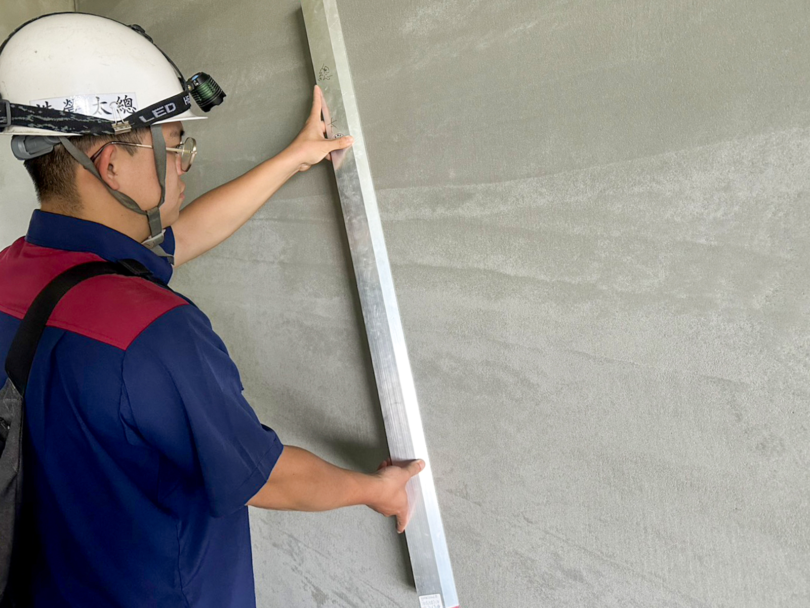 8F室內泥作粉光打底完成後，以整平尺查驗完成面水平度與垂直度