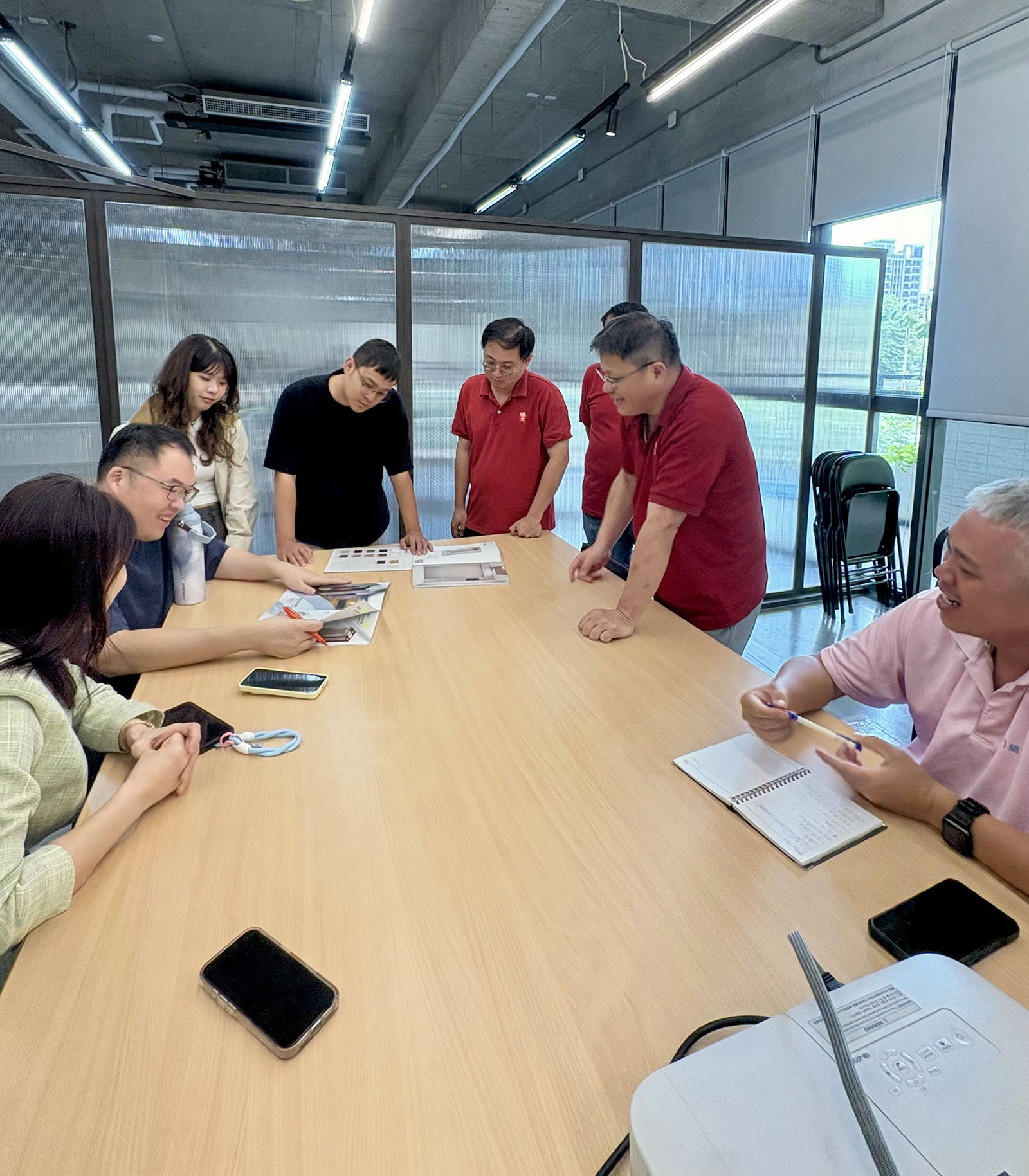 團隊於會議室熱烈討論電梯內裝材質與色彩搭配，檢視收邊品質