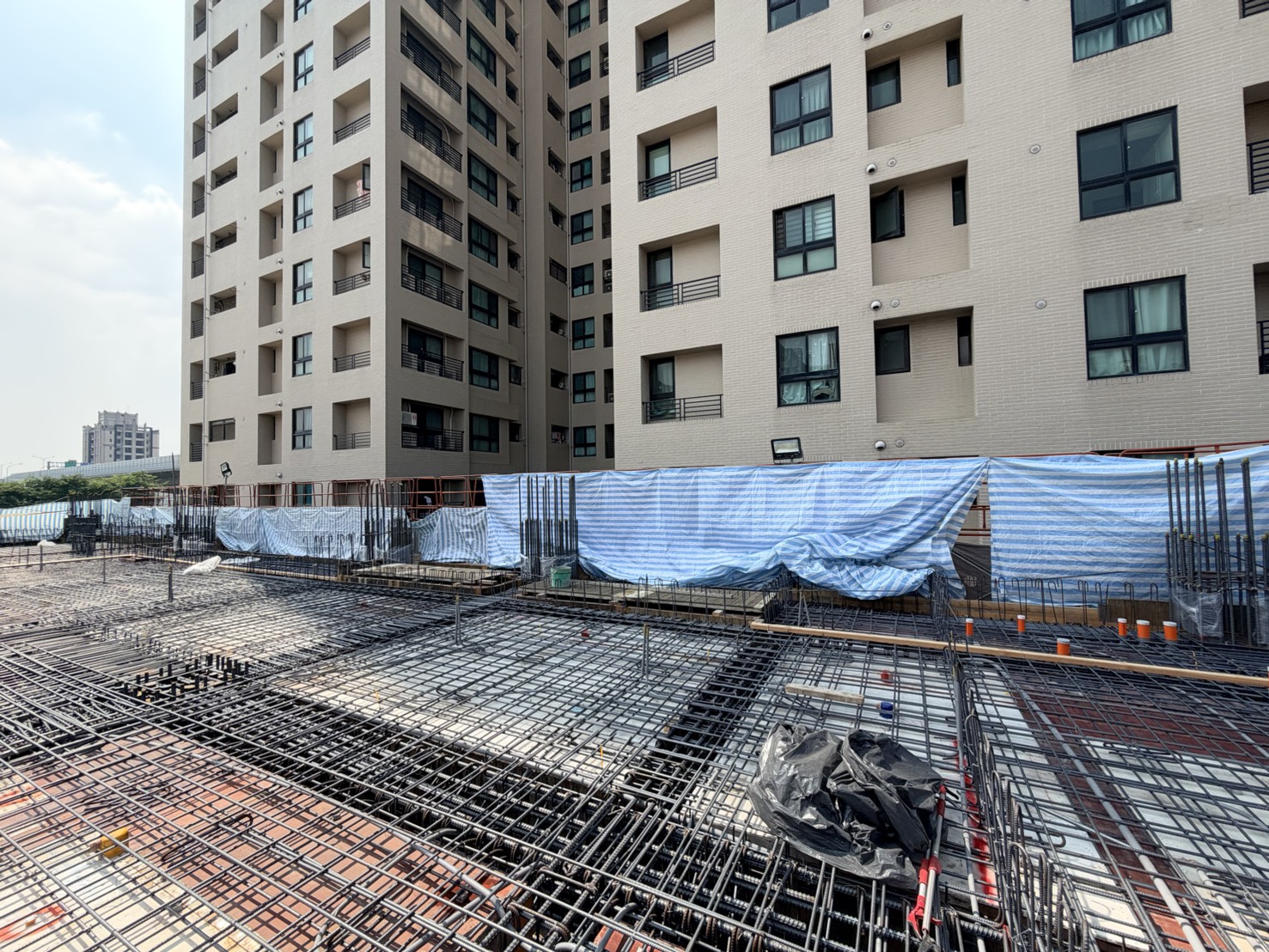 緊鄰住宅社區工區周邊主動架設高空防護帆布防止泥漿飛濺污染